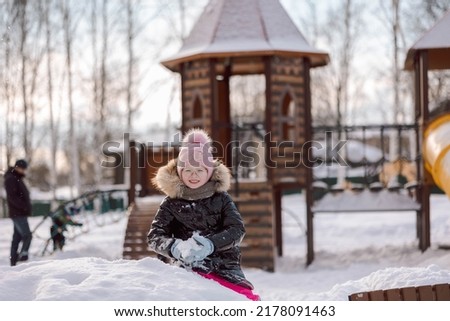 Little girl walks outdoors on winter snowy day in park. High quality photo