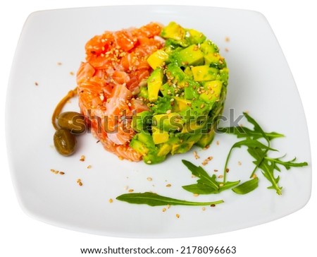 Salmon tartare with avocado served on white plate in restaurant. Isolated over white background