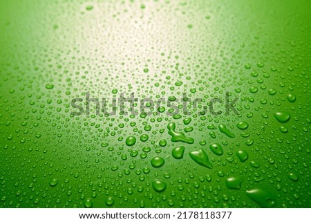 Full frame of clean green background covered with small round shaped drops of clear water flowing down in light room