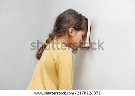 Sad and tired caucasian girl with dyslexia holds a wall. The child learns to speak and read correctly Royalty-Free Stock Photo #2178126871
