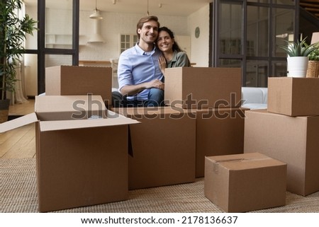 Happy millennial Caucasian couple feel overjoyed unpacking on moving day to new house. Smiling young man and woman renters unbox packages relocate to own apartment or home together. Rent concept. Royalty-Free Stock Photo #2178136637