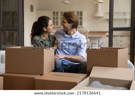 Happy millennial man and woman sit relax on sofa in living room enjoy moving day to new apartment together. Smiling young Caucasian couple renters celebrate relocation to own home. Rental concept. Royalty-Free Stock Photo #2178136641