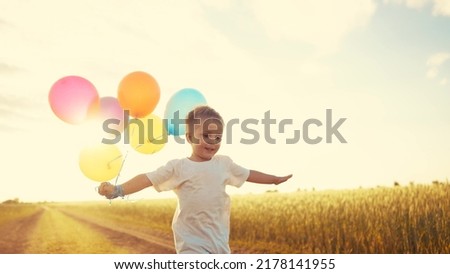 little baby boy run with balloons in the park in nature. happy lifestyle family holiday birthday kid dream concept sun. a little baby with colorful balloons run with the road in the field park