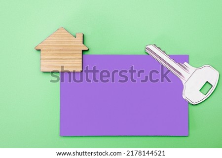 The concept of mortgage, sale and rental of housing and real estate. Business card with a key to the apartment and a mock-up of a wooden house. Copy space. Mock-up