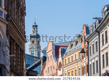 Horizontal photo of the traditional colorful architecture on Tirgonu street in the historical center in the Old Town of Riga, Latvia, with the tower of the City Hall and blue sky in the background.