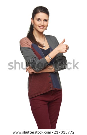 Smiling young woman in cardigan gesturing thumb up, looking at camera, over white background