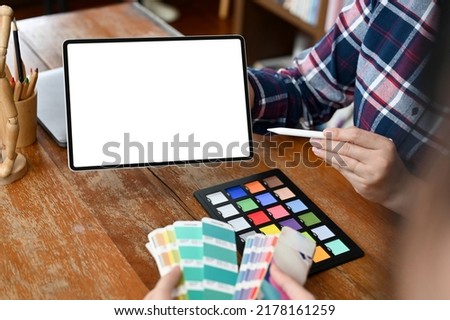 A team of graphic designer having a meeting in the office, A female graphic designer holding a blank tablet touchpad screen. cropped shot