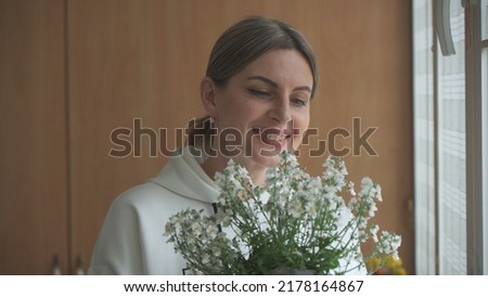 Young woman with bouquet in her hands, looks at flowers and smiles.