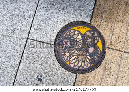 Soft color pattern of Japanese handball craft decorated on Japanese manhole cover. The letters on the cover means Matsumoto—name of the City and Temari—Japanese traditional handball craft.