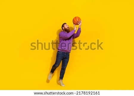 Full length photo of excited cool man wear violet sweatshirt throwing basketball ball isolated yellow color background