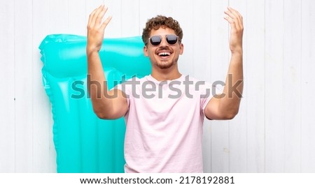 young man feeling happy, amazed, lucky and surprised, celebrating victory with both hands up in the air. holidays concept