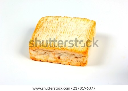 A square of Le Roussot cheese on a white background. Le Roussot is a Carré des Vosges, a soft, square-shaped cheese with the full taste that is typical of the local mountain region.