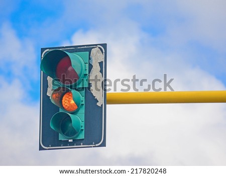 orange light in a traffic light under a blue sky