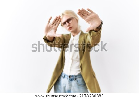 Beautiful caucasian business woman standing over isolated background doing frame using hands palms and fingers, camera perspective 