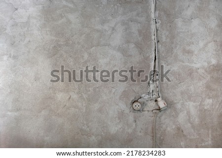 Rustic electrical socket on old limewashed plaster wall, indoor architecture detail, grunge background 