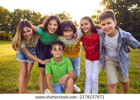 Kids having fun outdoors in summer. Group portrait of happy little school children in the park. Bunch of cheerful friends posing for a group photo, hugging, looking at the camera and smiling