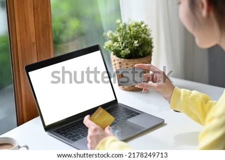 Back view of Asian woman in casual outfit entering typing credit card number on laptop to purchase items from an online store, order food, pay bills, Empty screen of laptop.