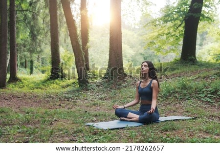 Woman sitting in the lotus position outdoors in nature, meditation and yoga concept Royalty-Free Stock Photo #2178262657