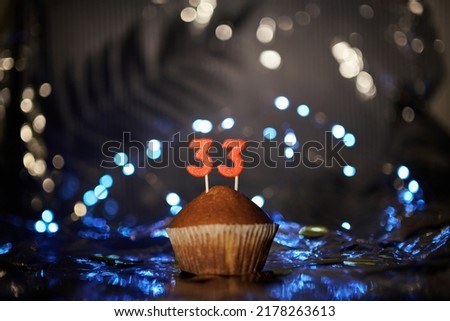 Digital gift card birthday concept. Tasty fresh homemade vanilla cupcake with number 33 thirty three on aluminium foil and blurred bright background in minimalistic style. High quality image