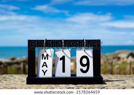 May 19 calendar date text on wooden frame with blurred background of ocean. Calendar date concept.