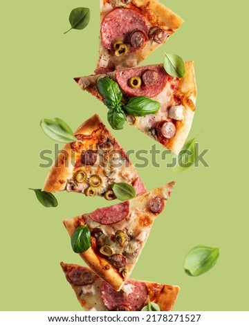 Flying food. Pizza slices with cheese, sausages, salami, olives and basil in levitation on olive background. Vertical orientation Royalty-Free Stock Photo #2178271527