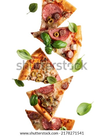 Flying food. Pizza slices with cheese, sausages, salami, olives and basil in levitation close up isolated on a transparent background. Vertical orientation
