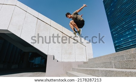 Young man jumping high over steps outdoors. Fit male free runner jumping over stairs in urban space. Royalty-Free Stock Photo #2178287213