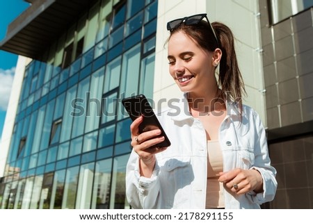 Portrait of smiling caucasian woman with white teeth chatting on phone searching information typing message, hold mobile device. Perfect healthy smile with veneer. Dental care. 