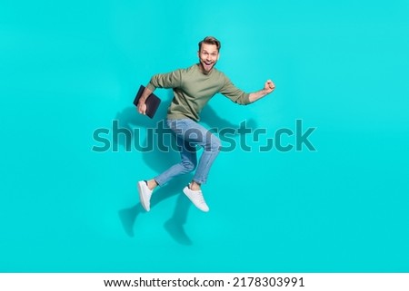 Full length photo of positive programmer man jump carry laptop run wear pullover isolated blue color background