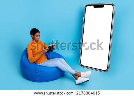Full size photo of focused concentrated nonbinary man person sit armchair reading book isolated on blue color background
