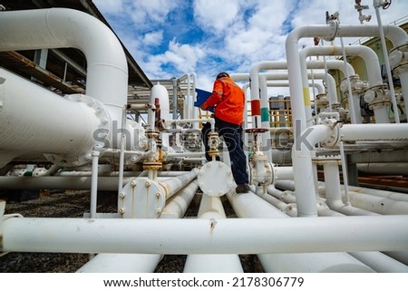 Male worker inspection at steel long pipes and pipe elbow in station oil factory during refinery valve of visual check record pipeline tank oil and gas industry Royalty-Free Stock Photo #2178306779