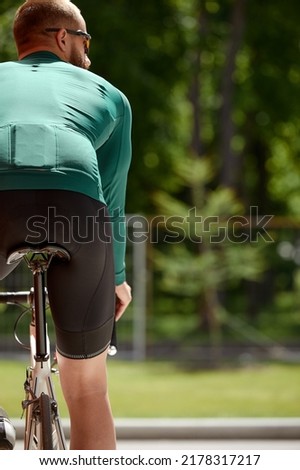 The young man rides a bicycle along around the city. Photo from the back. Outdoor vacation concept.