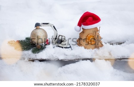 miniature model of toy construction excavator and sweet gingerbread in form of Christmas tree standing on snow in composition on theme of Christmas greetings for the construction business.