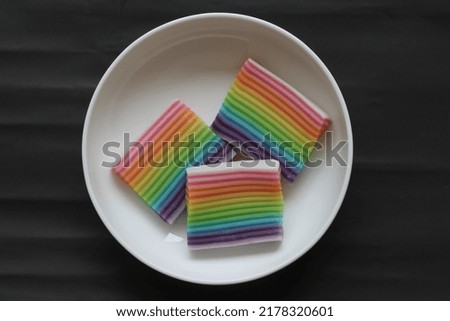 3 pcs of rainbow cake on a white plate on a black background