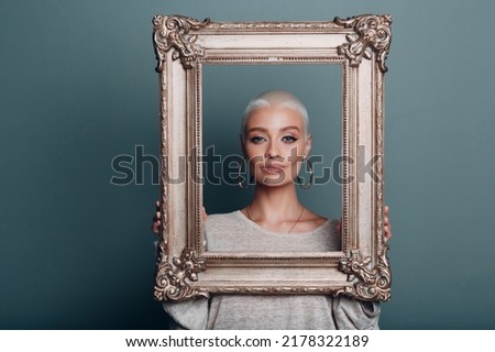 Museum restoration recovery renewal picture frame for painting art. Millenial young woman with short blonde hair holds gilded picture frame.