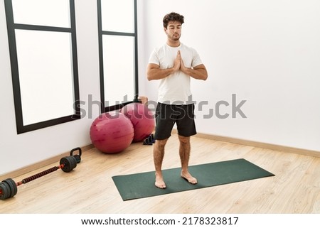 Young hispanic man training yoga exercise at sport center
