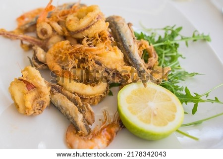Fried local seafood (Fritto misto di mare or Fritto misto di pesce ) squid rings, prawns, sardines, and octopus, with lemon on white plate. Popular food in Italy. 
 Royalty-Free Stock Photo #2178342043