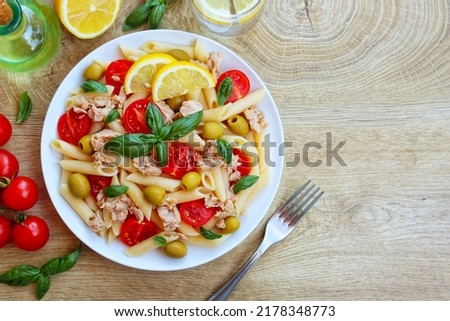 Italian Traditional Dish"Pasta fredda con tonno,pomodorini e olive",pasta salad with canned tuna,cherry tomatoes and olives on plate with wooden table background.Healthy Italian summer salad.Top view
 Royalty-Free Stock Photo #2178348773