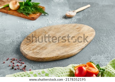 Food mockup. Empty wooden board on concrete table with cooking  ingredients. Wooden board  with spices, greens and tomatoes for menu. Food menu mockup. Cooking composition with empty place Royalty-Free Stock Photo #2178352195