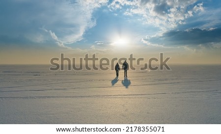 The two travelers with backpacks walking trough the snow field