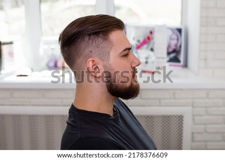 Brunette man with stylish haircut on barbershop background Royalty-Free Stock Photo #2178376609