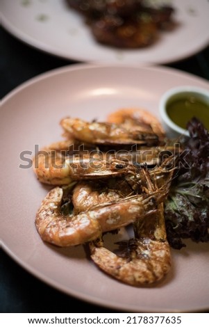 grilled king prawns, josper, smoker, mangal, fried on a fire. Beautiful appetizing seafood is laid out on a round plate at a table served with a white tablecloth.