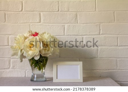 Blank photo frame mockup and peonies bouquet on the table.Copy space