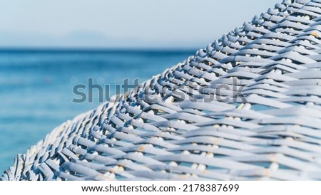 Wicker beach umbrella. Close-up of wicker blue beach umbrella and sea on the background. Vacation concept background. Summer holiday concept. Selective focus included