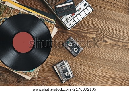 Vinyl records, cassette tapes and cassette recorder on wooden table. Retro music style. 80s music party. Vintage style. Analog equipment. Stereo sound. Back to the past Royalty-Free Stock Photo #2178392105