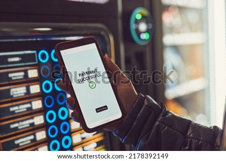 Consumer paying for product at vending machine using contactless method of payment with mobile phone. Woman using payment app on smartphone to buy product. Female hand holding smart phone with pay app Royalty-Free Stock Photo #2178392149