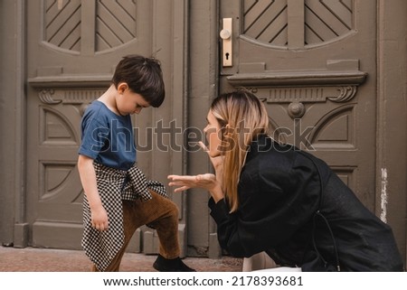 Mother scolds her son on the street. A child cries, a woman shakes her finger because of the boy bad behavior, while walking to home. Rule of conduct. Woman sitting, boy cover his face and cry. Royalty-Free Stock Photo #2178393681