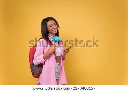 African American student woman using smartphone standing over isolated yellow background with a happy face standing and smiling with a confident smile