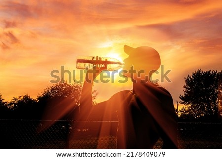 Silhouette of a man drinking water during heat wave Royalty-Free Stock Photo #2178409079