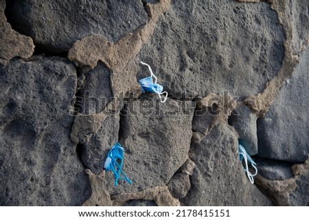 Masks stuck by tourists in the cracks on the cliff of Playa de Las Canteras Las Palmas de Gran Canaria